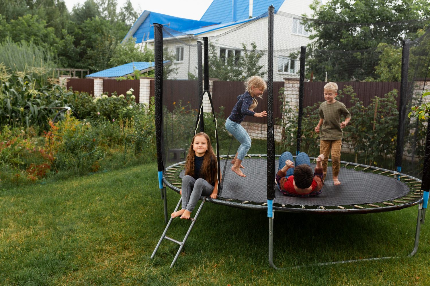 A smiling family enjoying time together while jumping on a backyard trampoline surrounded by greenery.