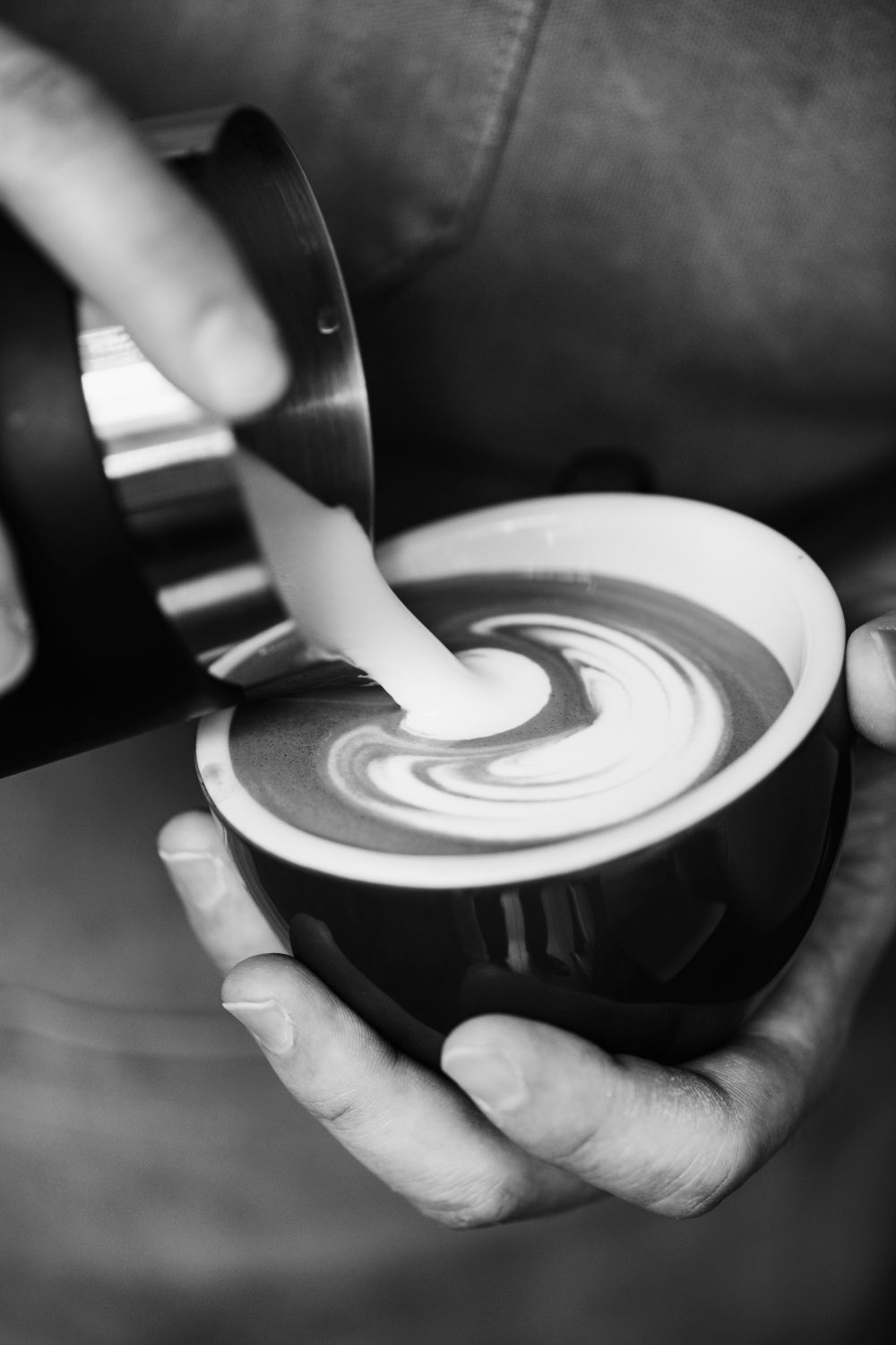 A barista preparing a cup of freshly brewed specialty coffee in a cozy café setting.