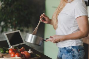 Realistic kitchen setup with essential cookware: cast iron skillet, non-stick pan, saucepans, deep oven dish, and large pot on a wooden countertop.